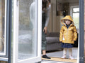 Mother and daughter standing by opened door to garden