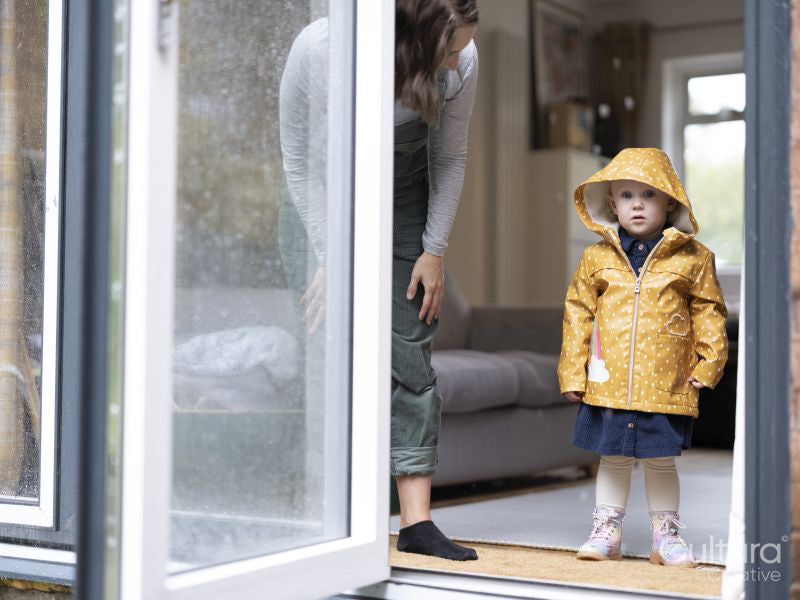 Mother and daughter standing by opened door to garden