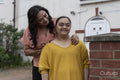 Portrait of woman with down syndrome daughter in front of house