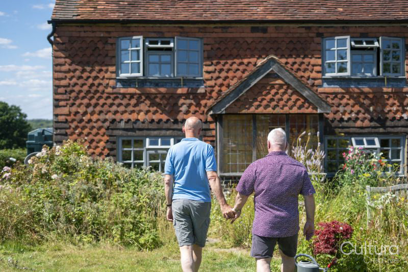 Senior male couple holding hands in garden