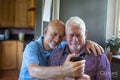 Senior male couple using smart phone at home