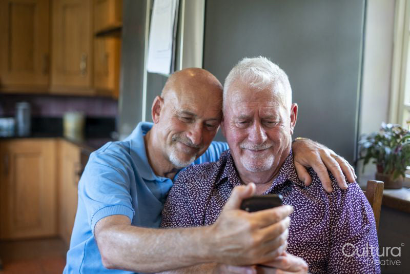 Senior male couple using smart phone at home