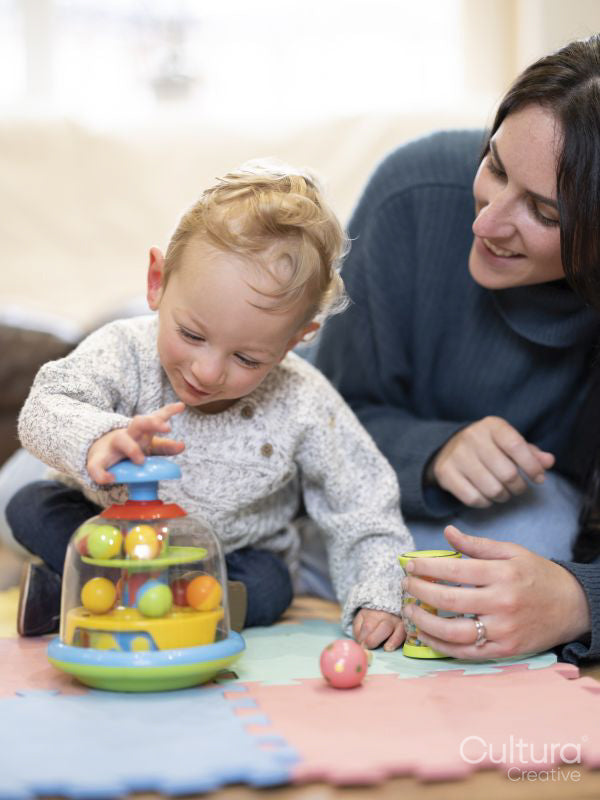 Smiling mother looking at son playing with spinning top