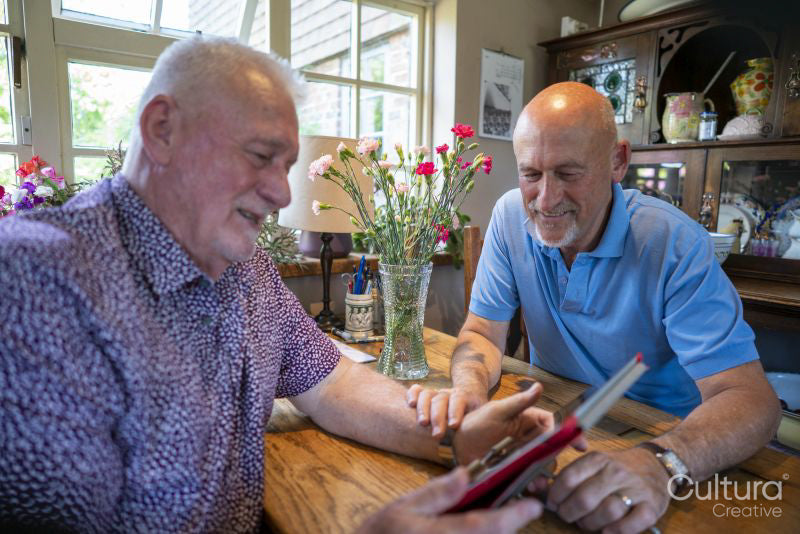 Senior male couple using tablet at home