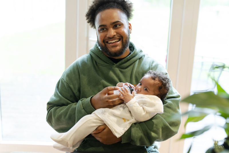 Smiling father feeding baby daughter at home