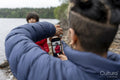 Mother photographing son by lake on hike