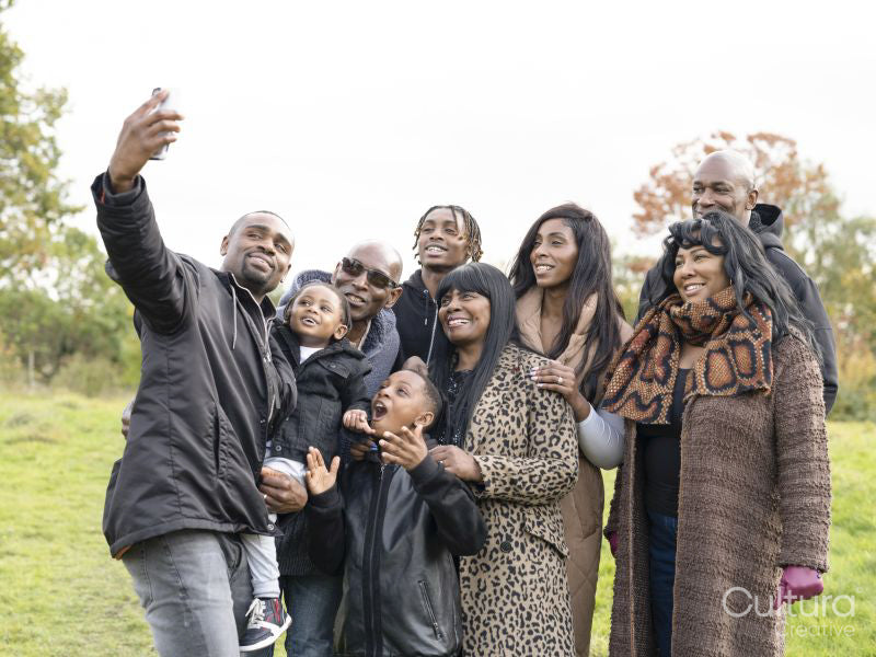 Portrait of multi-generational family taking selfie in meadow