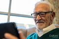 Senior man in eyeglasses using digital tablet in nursing home