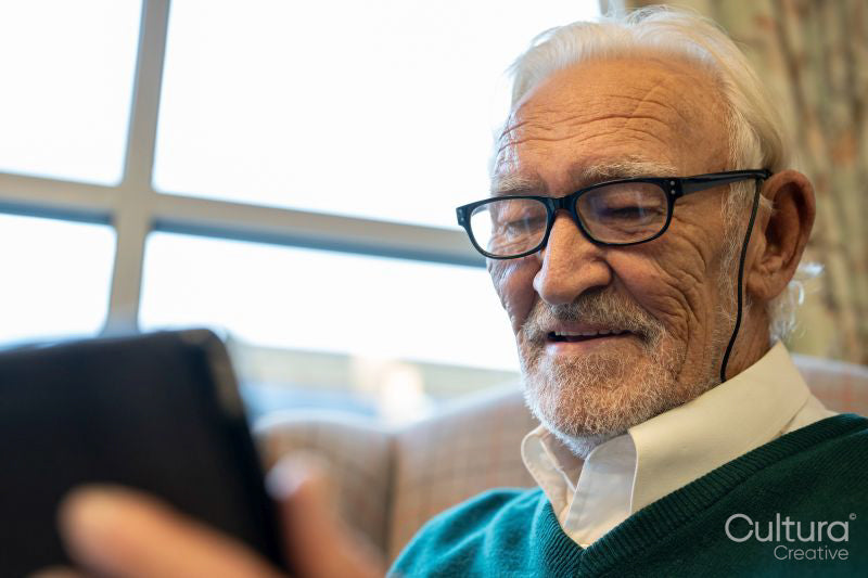 Senior man in eyeglasses using digital tablet in nursing home