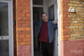 Portrait of mid adult man standing in doorway of house