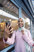 Young woman in hijab taking selfie in front of cafe