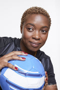 Studio portrait of smiling female soccer player with ball