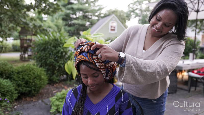 Mother putting traditional headdress on daughter