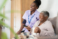 Caregiver and senior woman watching TV and laughing