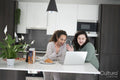 Two women looking at laptop in kitchen