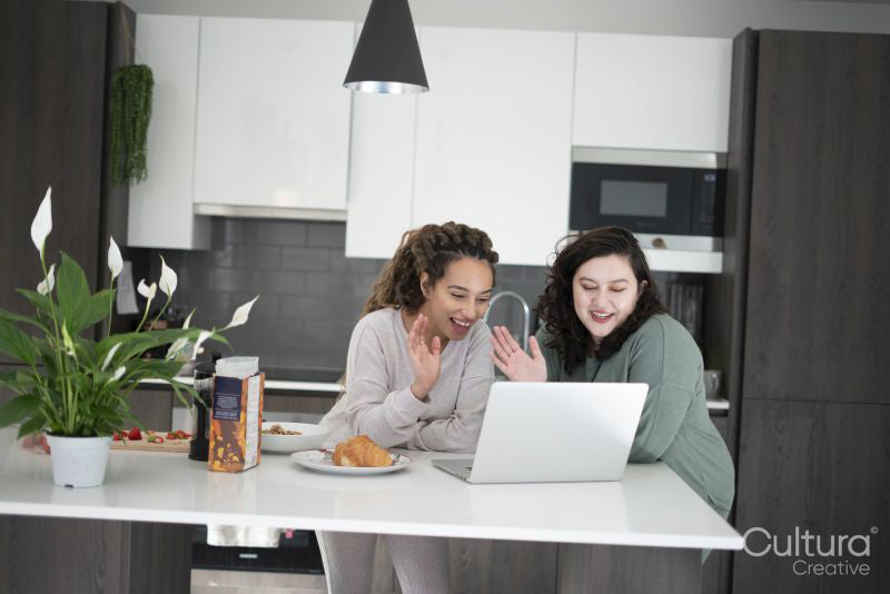 Two women looking at laptop in kitchen