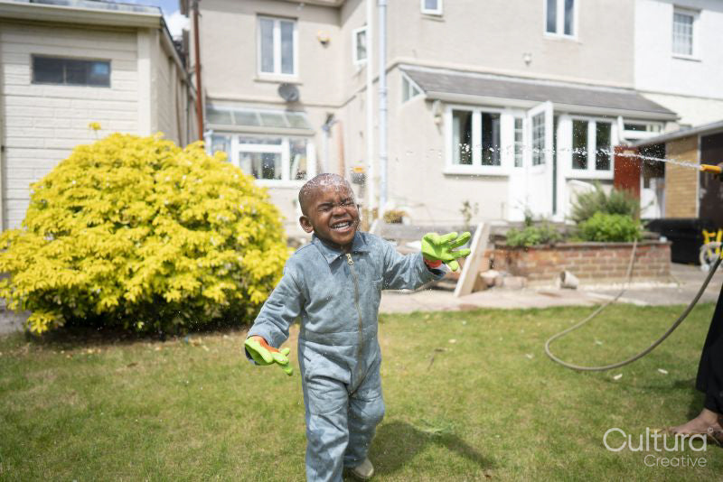 Boy splashed with water from garden hose