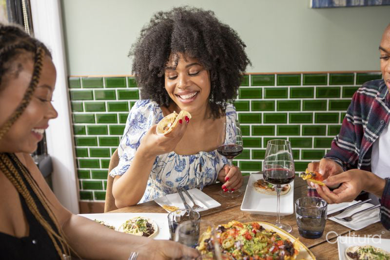 Smiling friends enjoying Me,ican food at restaurant table