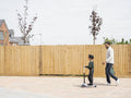 Boy on push scooter walking with father to school