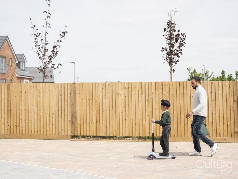 Boy on push scooter walking with father to school