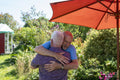 Senior male couple hugging in garden