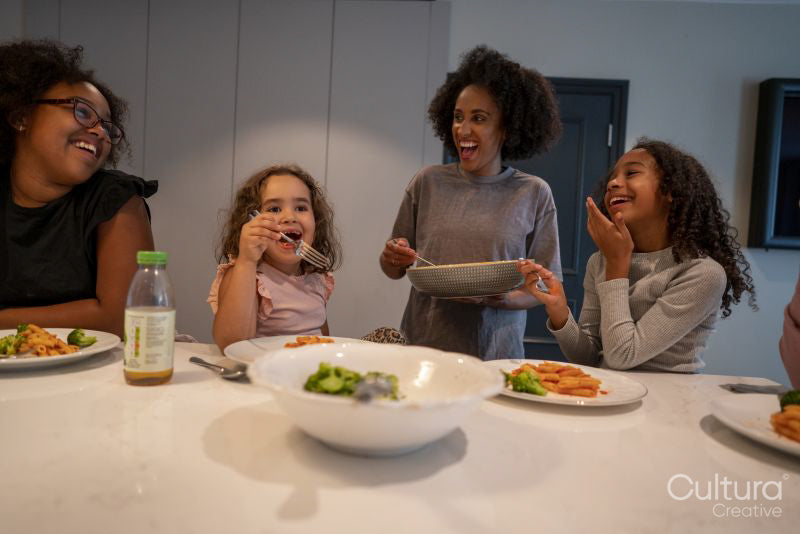 Mother with three daughters enjoying dinner in kitchen