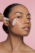 Studio portrait of beautiful woman doing face massage with jade roller