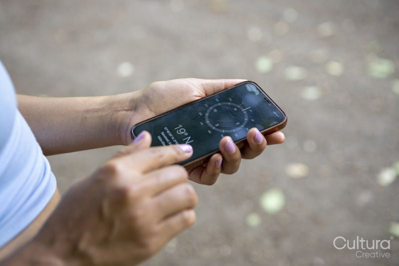 Young woman using compass on smart phone, close up of hands