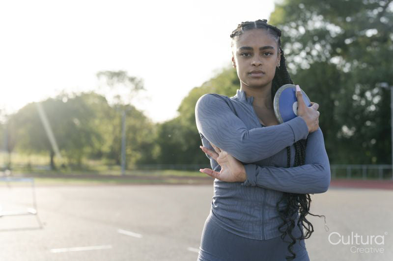 Portrait of female athlete holding discus at stadium