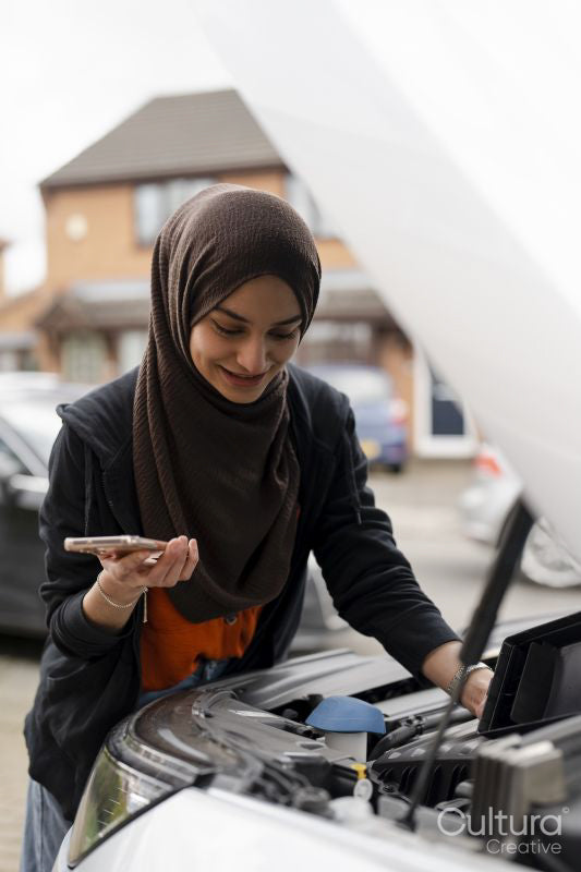 Woman wearing hijab looking into car engine
