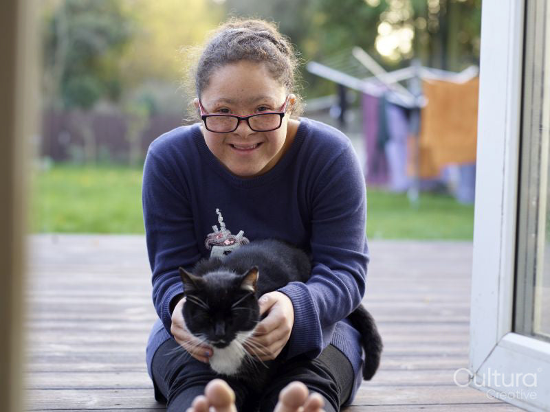 Portrait of girl with Down Syndrome sitting on patio with cat