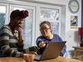 Mother with daughter with Down Syndrome using laptop at home
