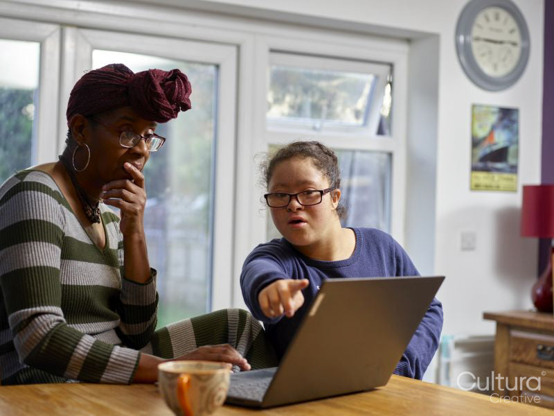 Mother with daughter with Down Syndrome using laptop at home