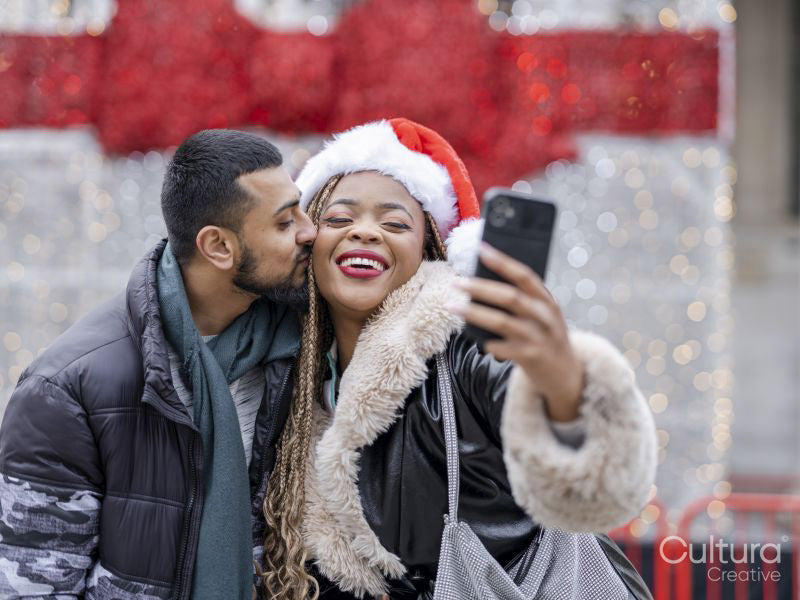 Young couple taking selfies against Christmas decorations