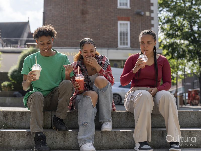 Friends laughing while drinking smoothies on steps