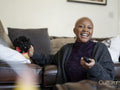 Smiling woman watching television while stroking dog at home