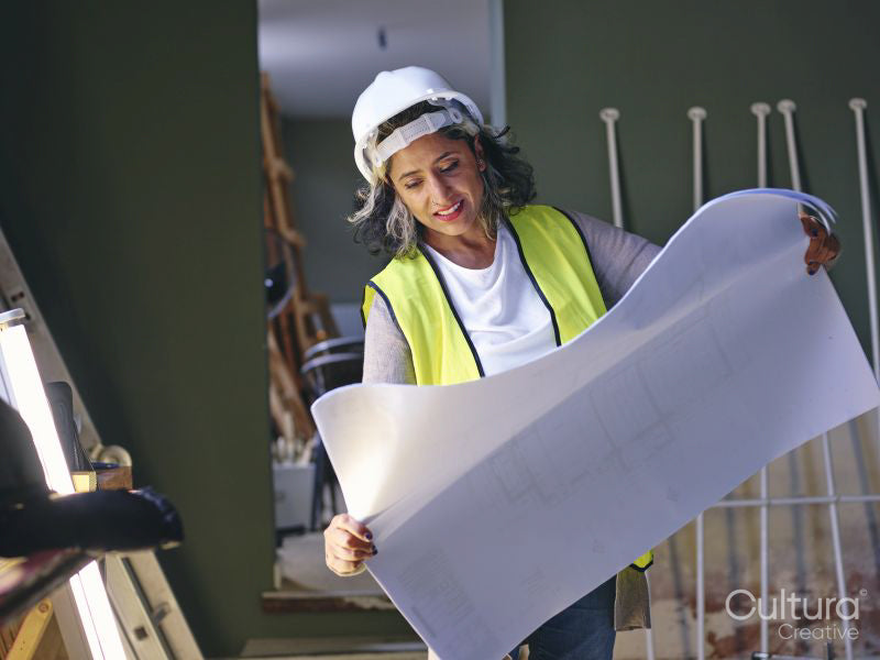 Woman in hardhat looking at blueprint