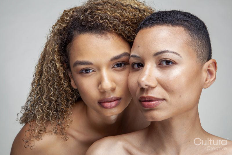 Studio portrait of two shirtless women cheek to cheek