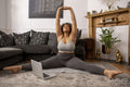Woman exercising in living room in front of laptop