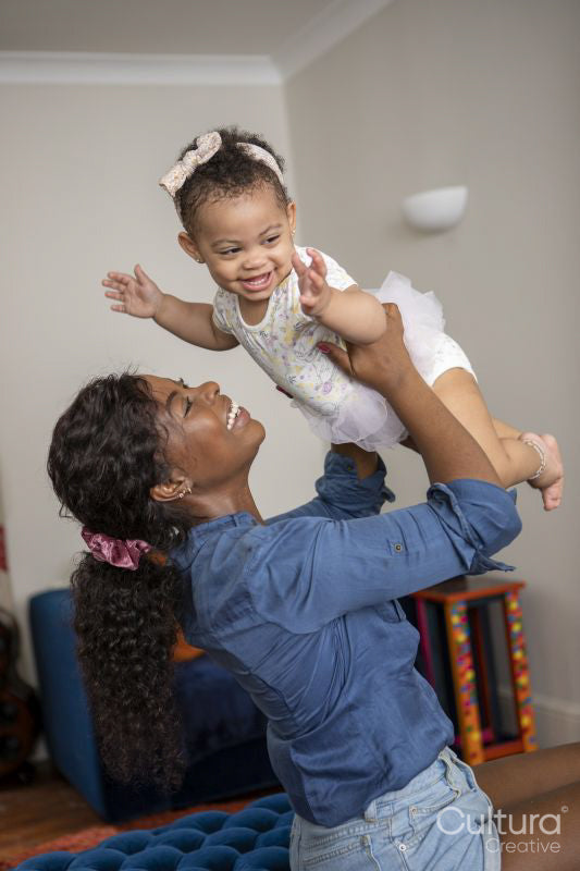 Mother playing with baby daughter at home