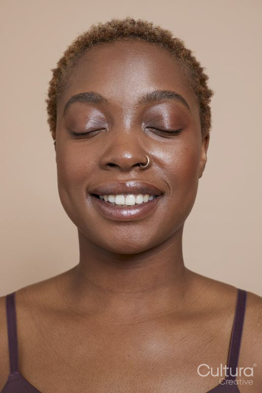 Studio portrait of smiling woman with nose ring and eyes closed