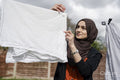 Woman wearing hijab hanging laundry in backyard