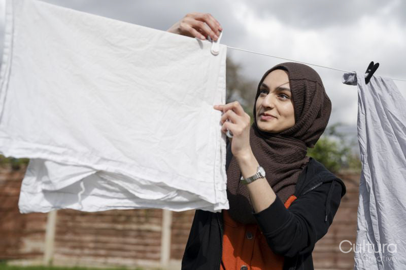 Woman wearing hijab hanging laundry in backyard