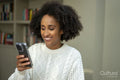 Smiling woman looking at smart phone at home