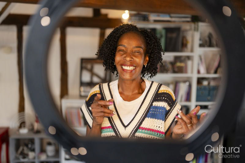 Smiling woman standing in front of ring light at home