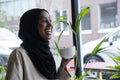 Smiling young woman in hijab drinking coffee in cafe
