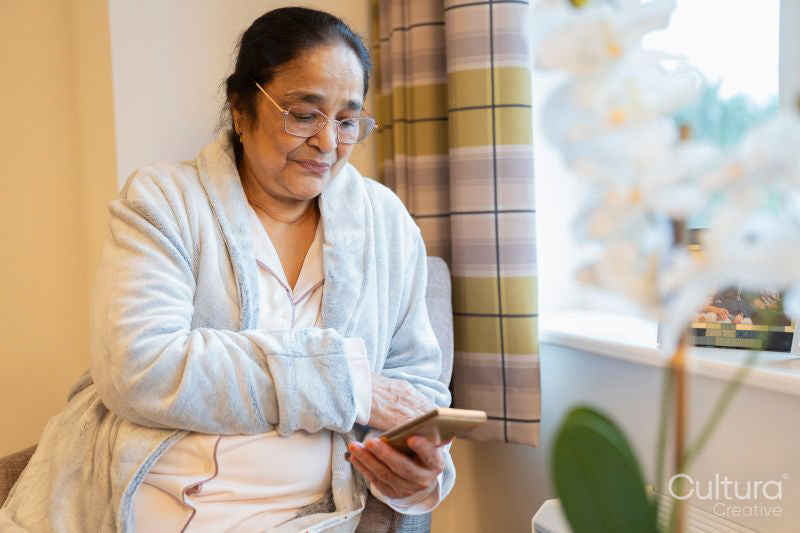 Senior lady sitting with phone at nursing home