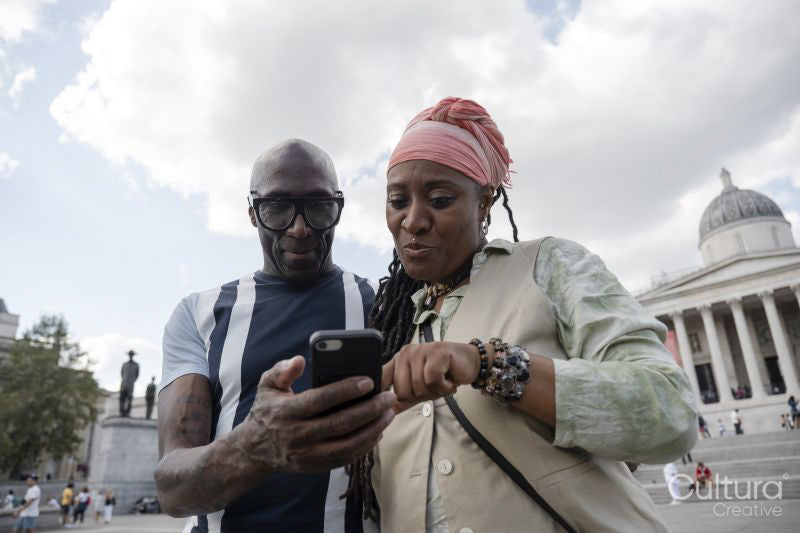Happy mature couple using smartphone while visiting city