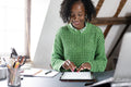 Smiling businesswoman working on digital tablet by desk in office