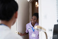 Smiling nurse standing at door and talking to female doctor sitting in office